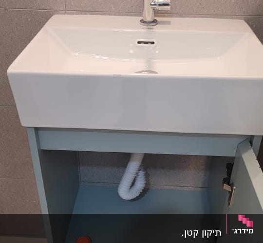 ארון אמבטיה מותקן עם כיור לבן, ברז וצינור ניקוז